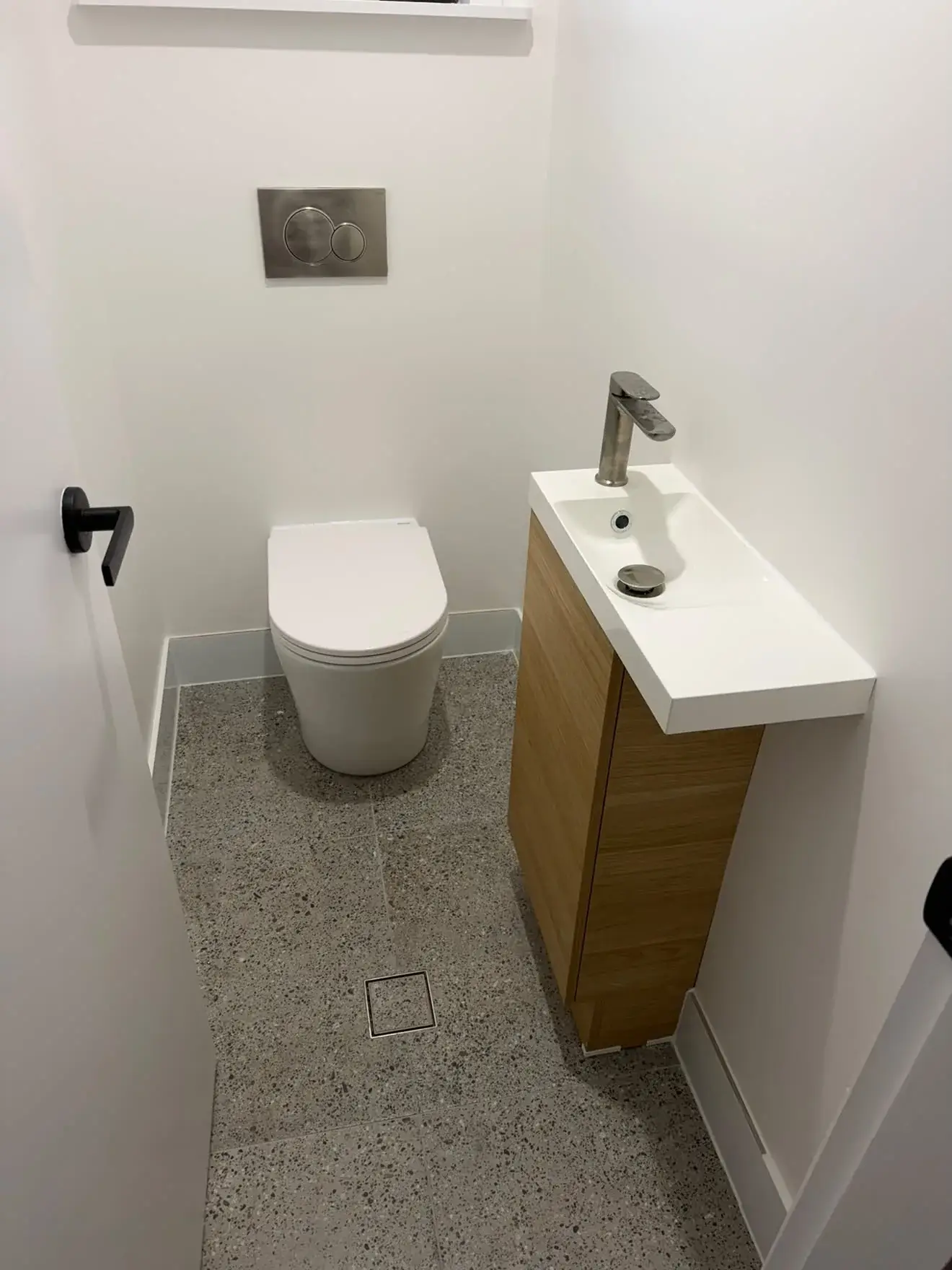 Powder room: back-to-wall toilet, in-wall cistern and a compact timber vanity, Bateau Bay.