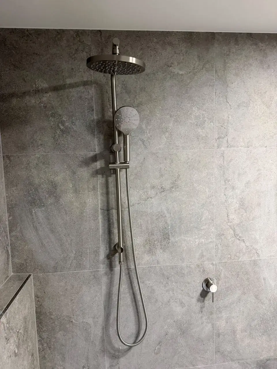 Brushed nickel rail shower and wall mixer on stone-look tile, Lake Munmorah.