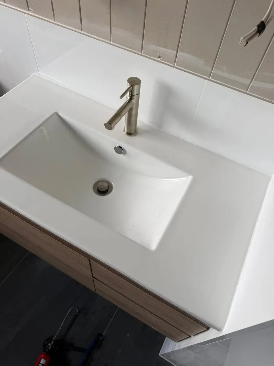 Vanity basin and brushed tapware going on at fit-off, Wyee Point.