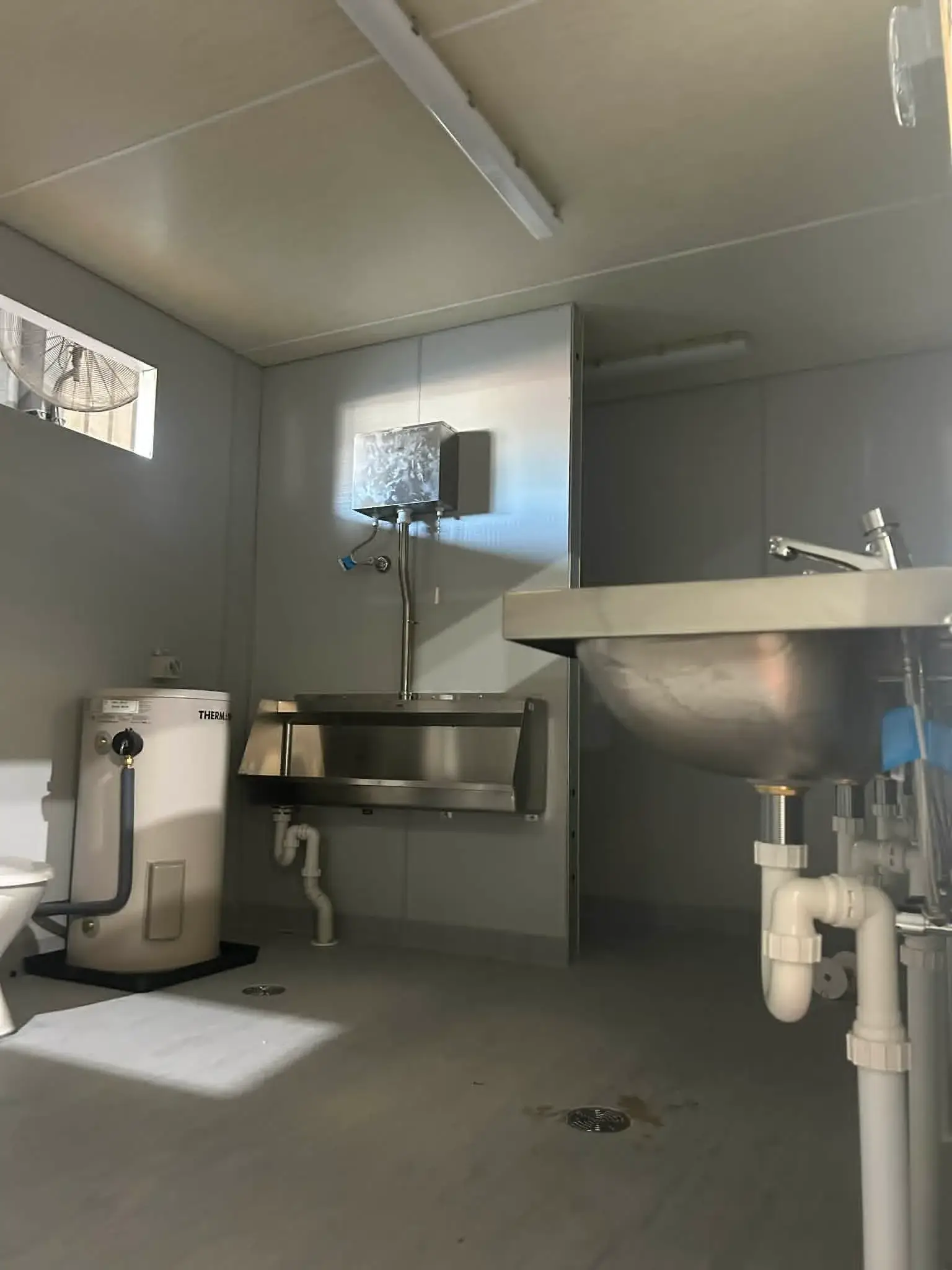 Amenities module: stainless urinal, Thermann storage and trough wastes