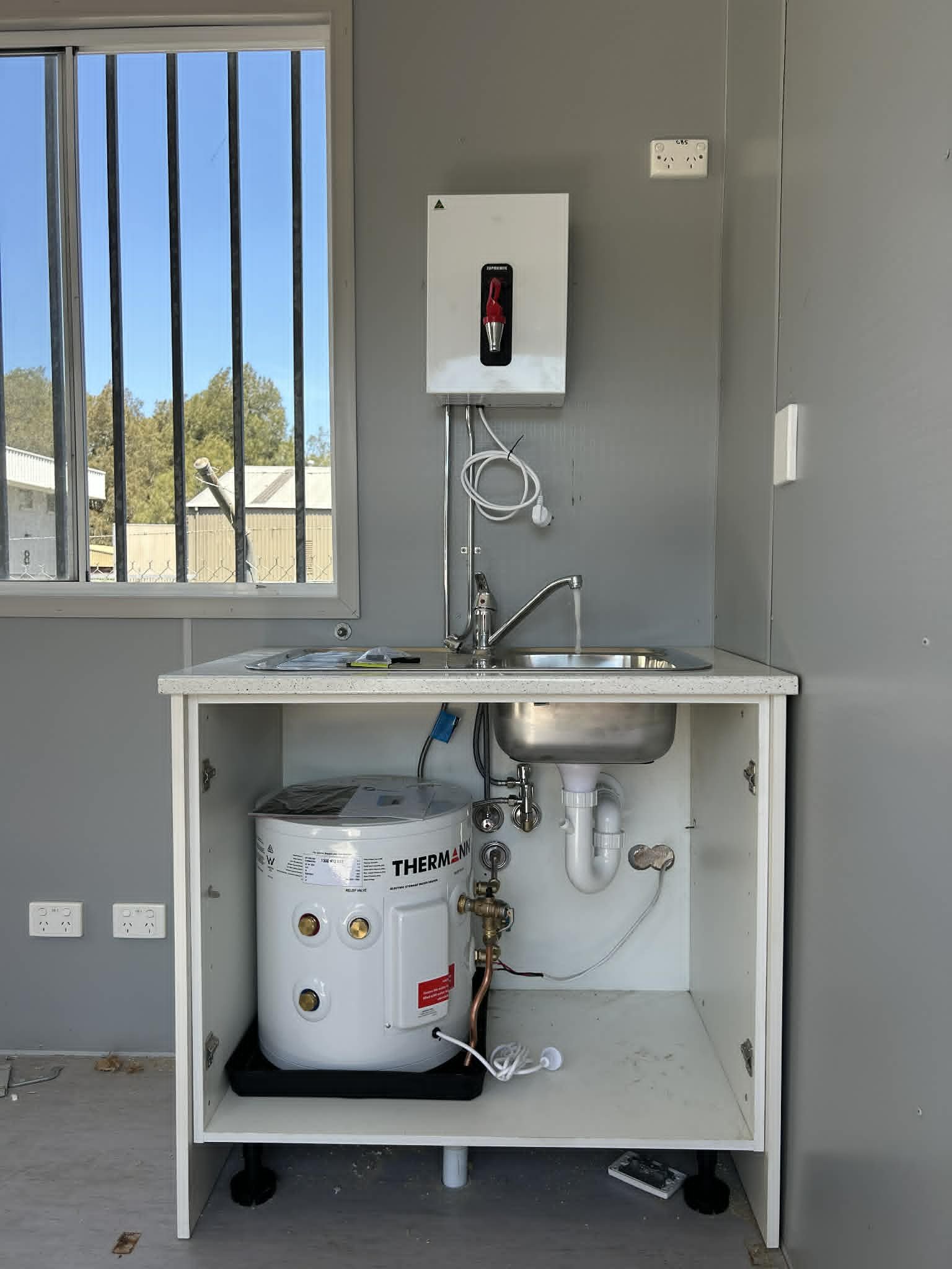 Site kitchenette: stainless sink, mixer running, under-bench Thermann storage