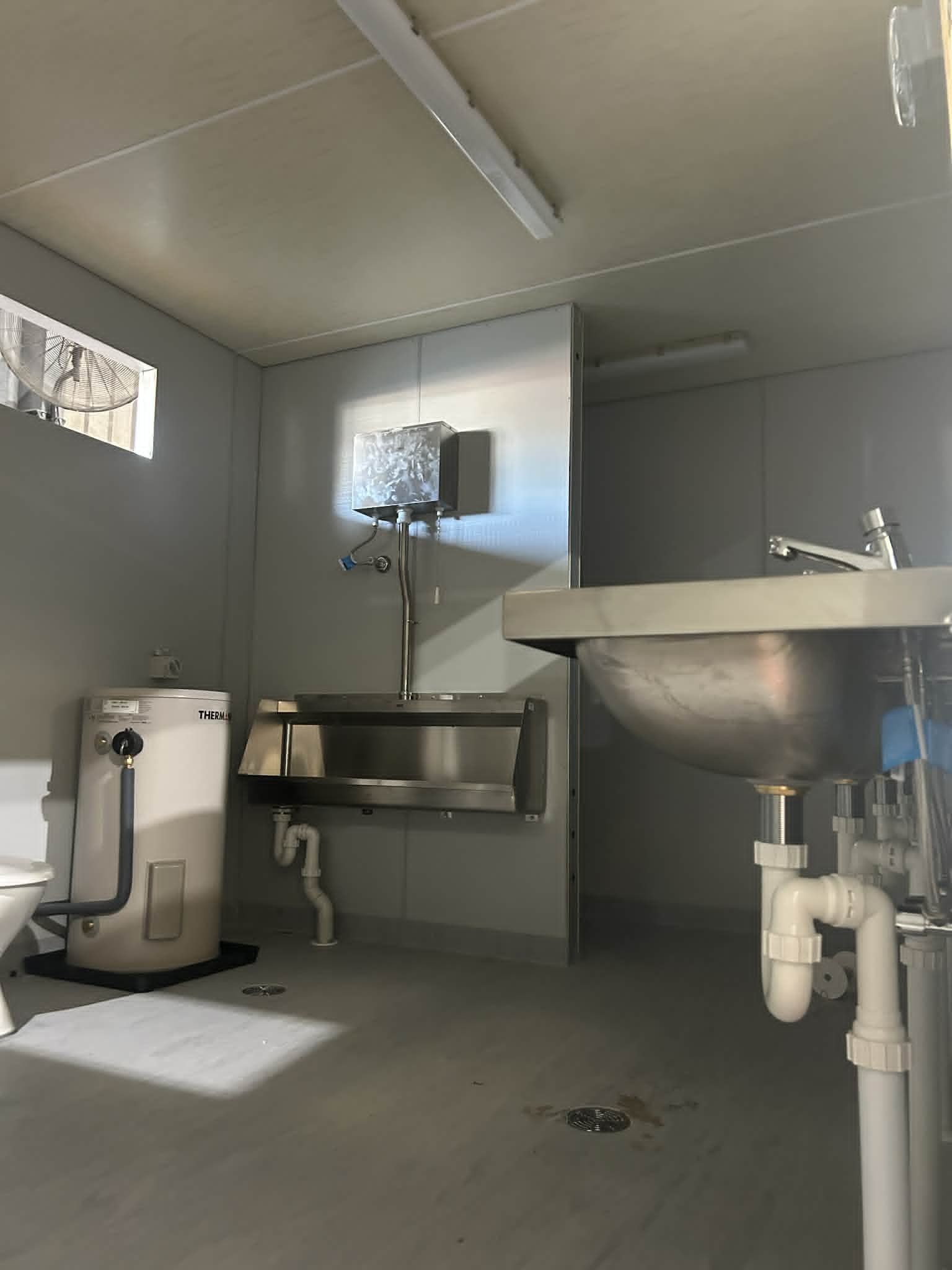 Amenities module: stainless urinal, Thermann storage and trough wastes