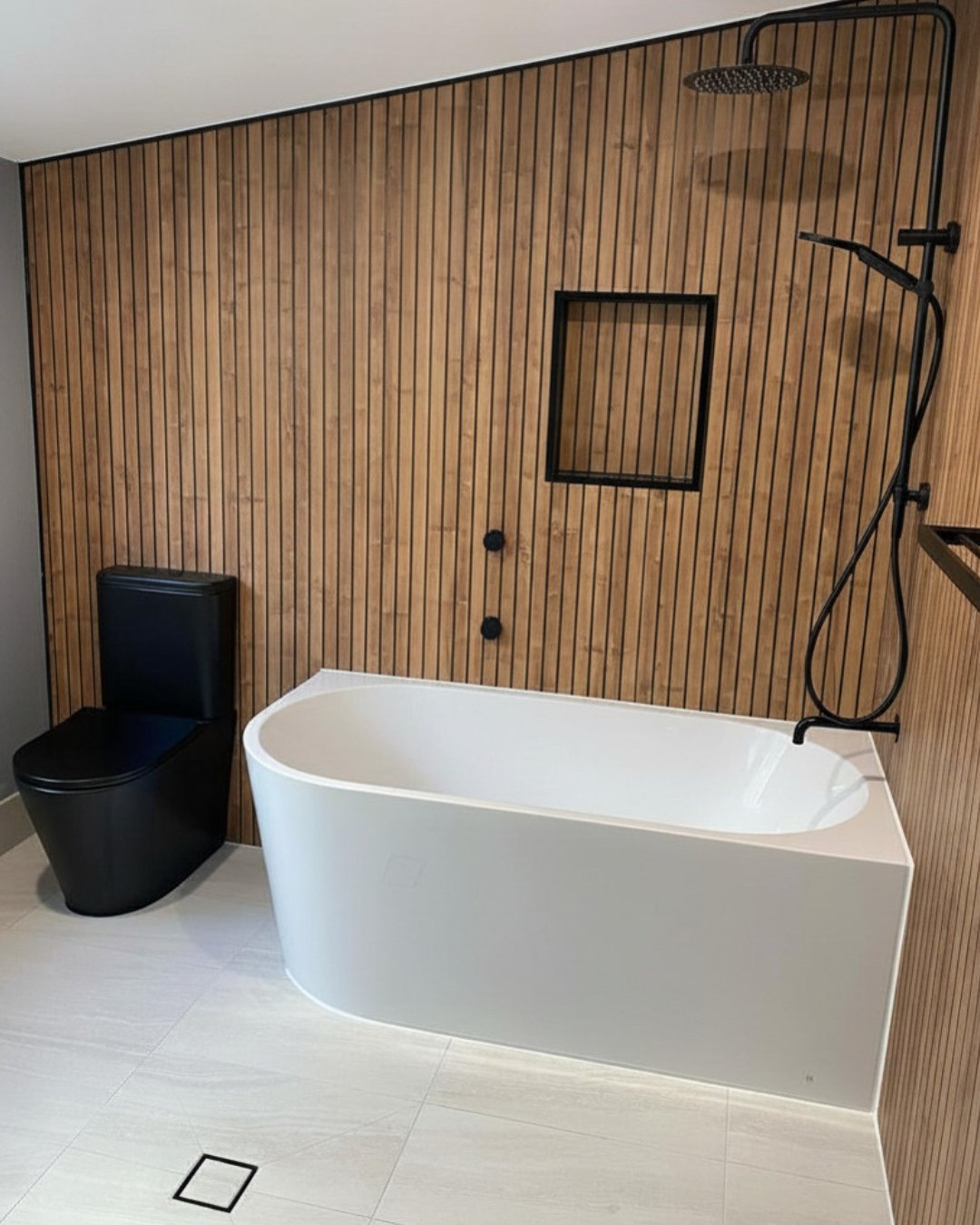 Bathroom, Gwandalan: timber slat wall, black toilet, white bath and black rain shower.