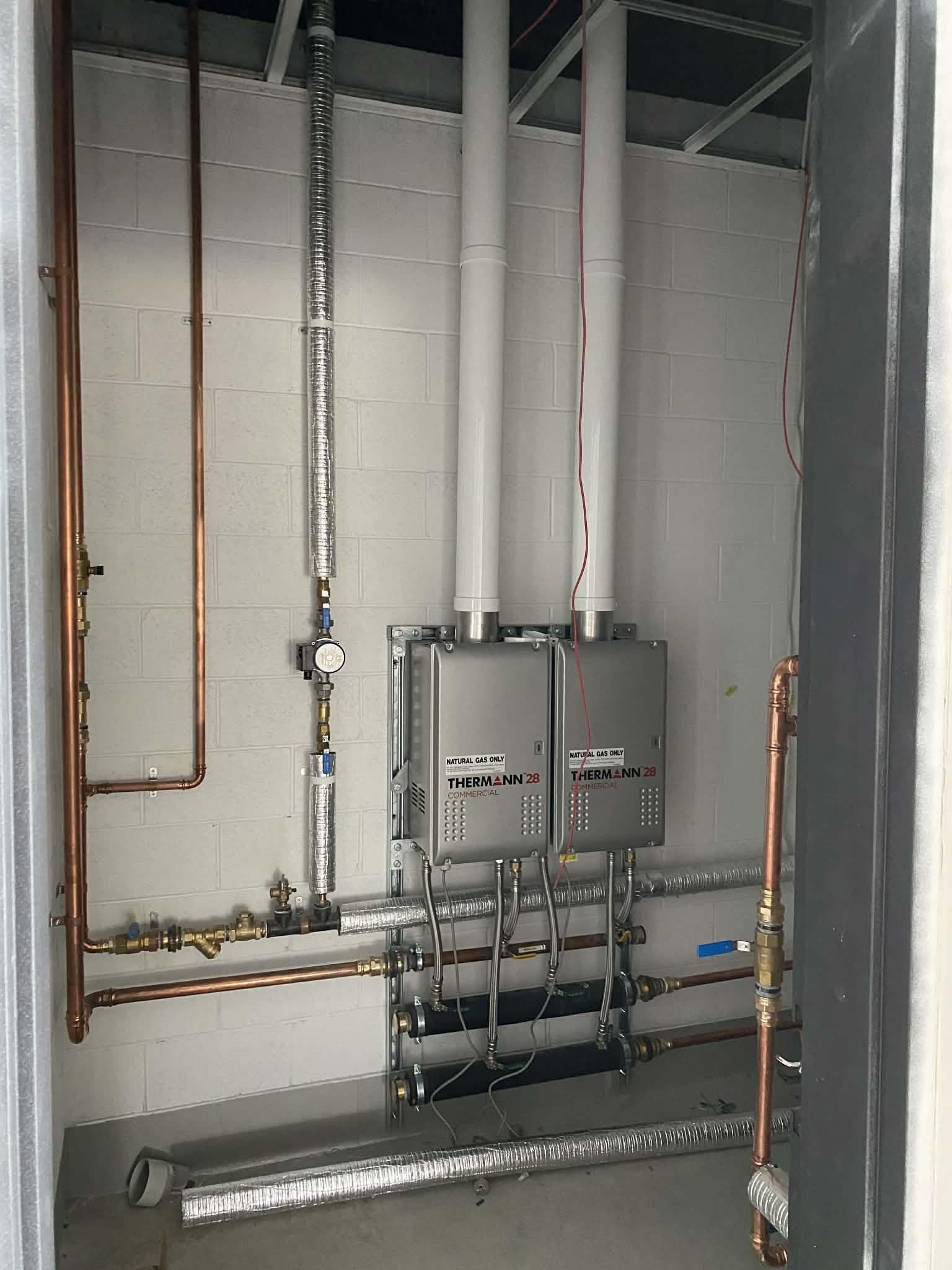 Twin Thermann 28 commercial continuous-flow units in a plant room