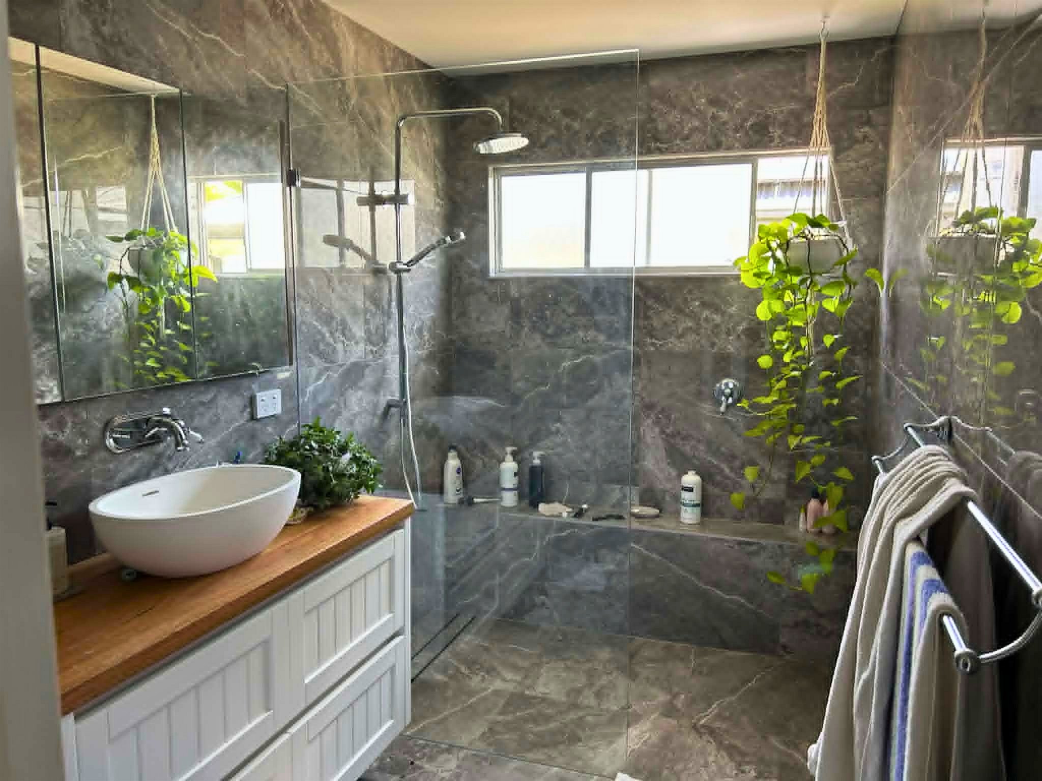 Finished bathroom, Mannering Park: vessel basin, timber vanity, marble tile and glass shower.