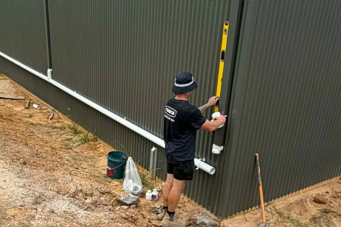 Checking a stormwater downpipe is plumb on a colorbond wall
