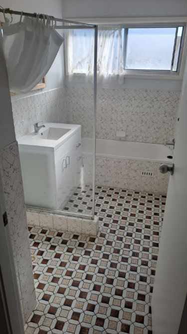 Original Newcastle bathroom from the doorway: vanity left, bath under the window