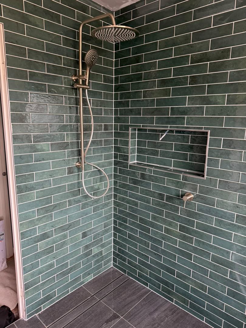 Green subway tiled shower: brushed nickel rail set, tiled niche and linear drain.