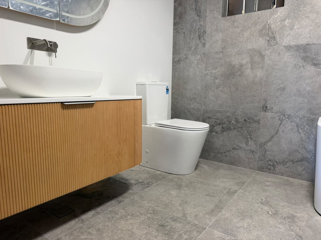Finished bathroom: vessel basin on a fluted timber vanity, wall mixer and back-to-wall toilet.