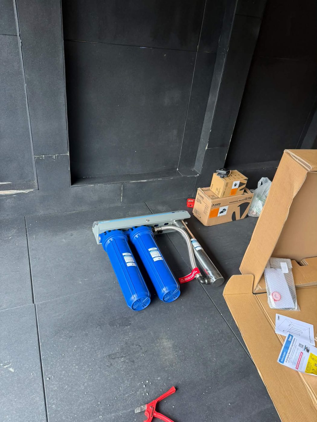 Multi-stage cartridges and the stainless UV chamber, laid out before the wall mount.