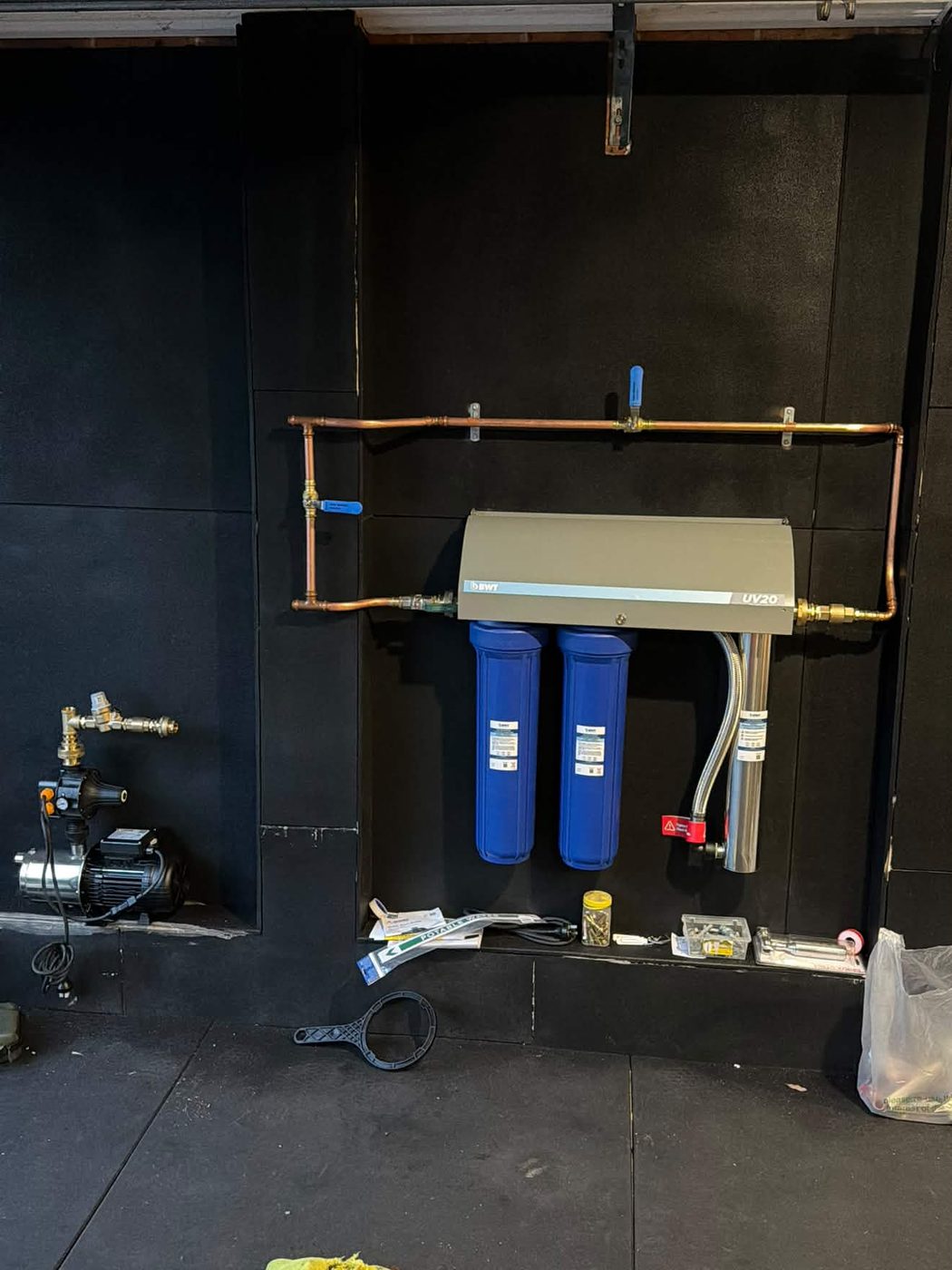 Filtration, UV and the mains-pressure pump set out along the garage wall.